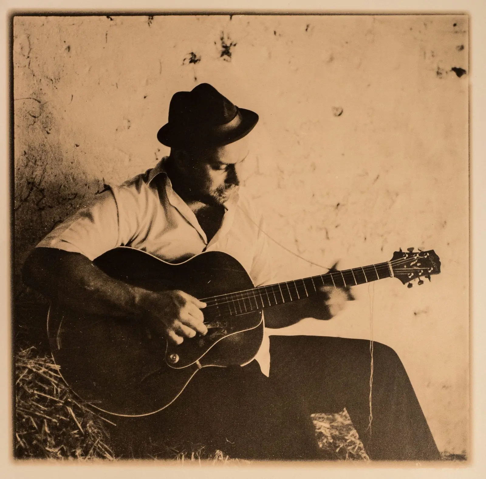 Big Creek Slim playing guitar in an archival sepia portrait
