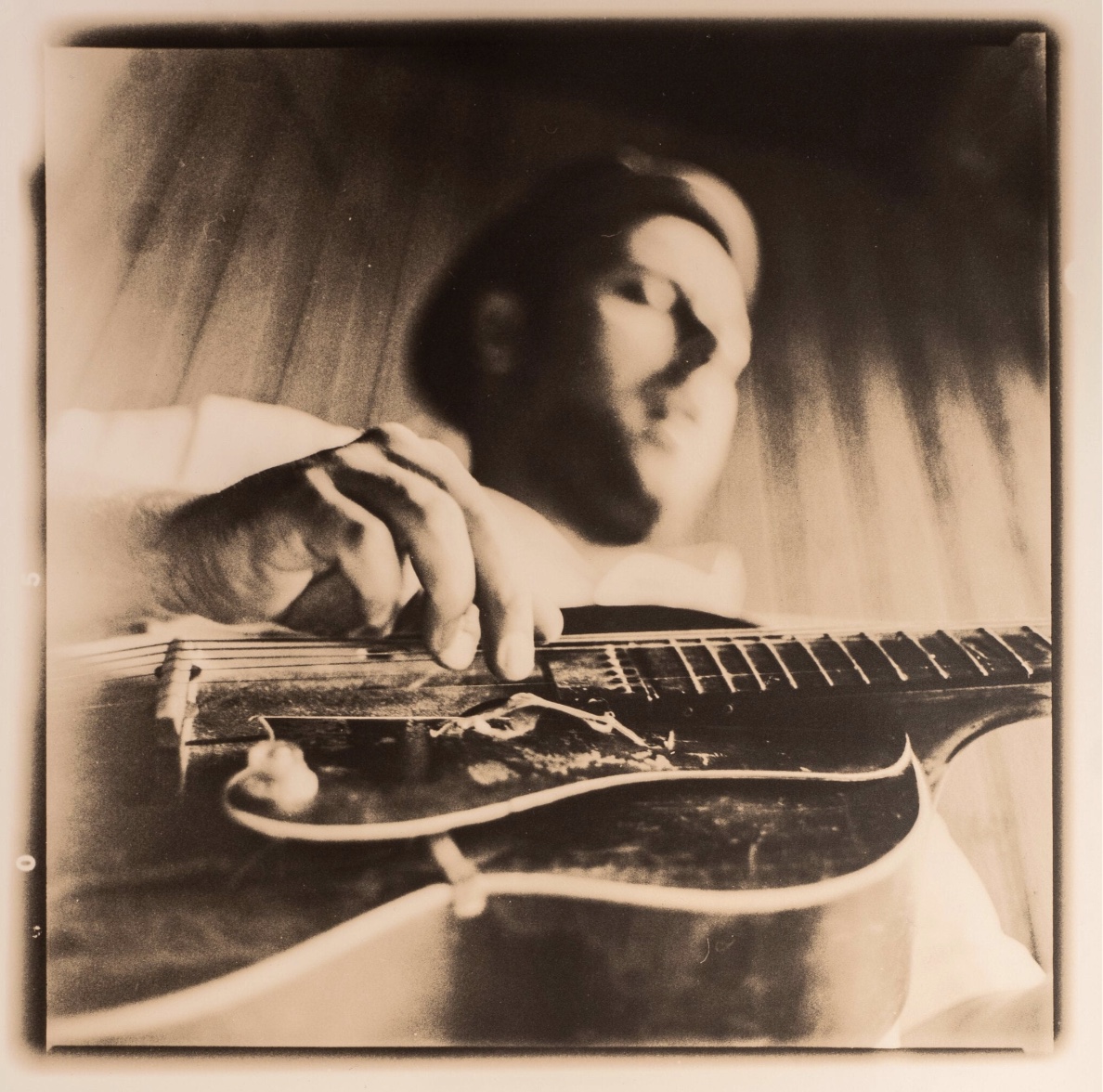 Sepia portrait of Big Creek Slim playing slide guitar