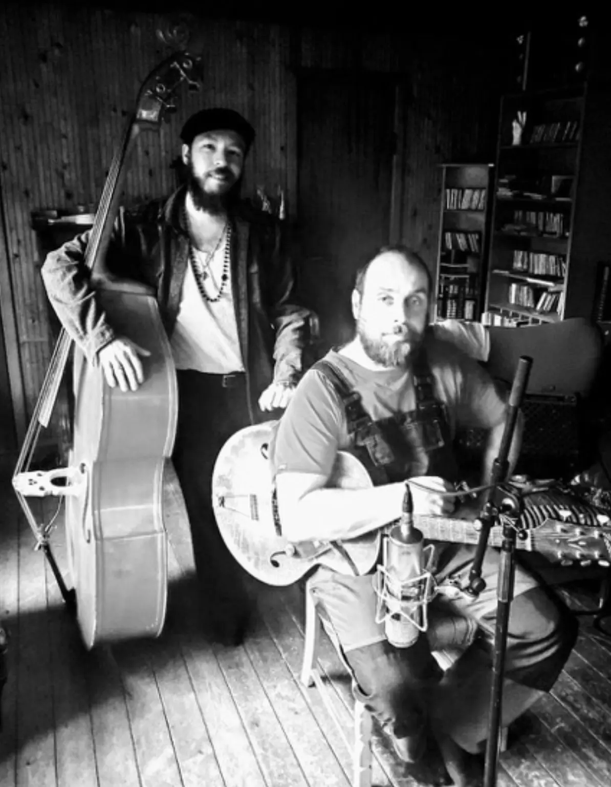 Big Creek Slim seated with his guitar beside an upright bass player in the recording room