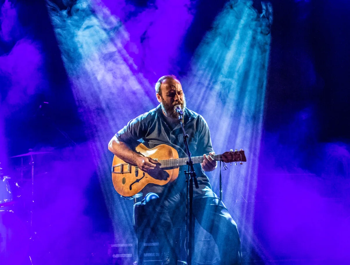 Big Creek Slim performing with guitar under blue and violet stage lights