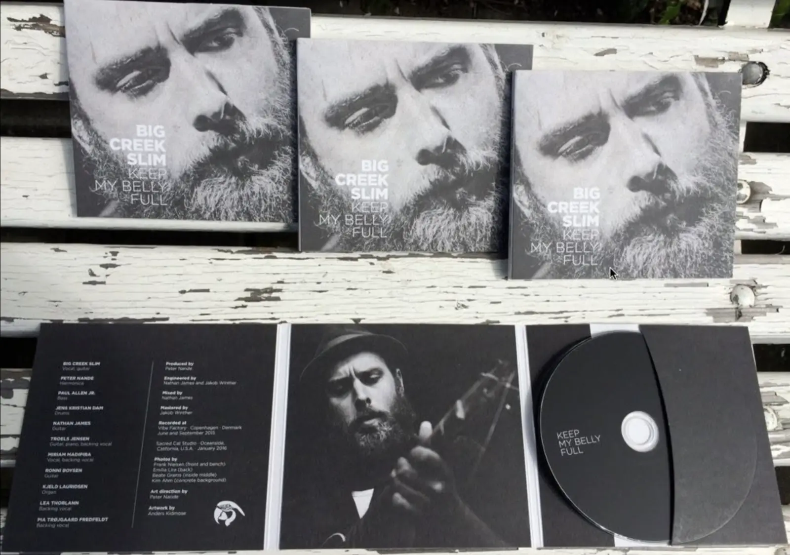Keep My Belly Full CDs and album packaging arranged on a weathered bench